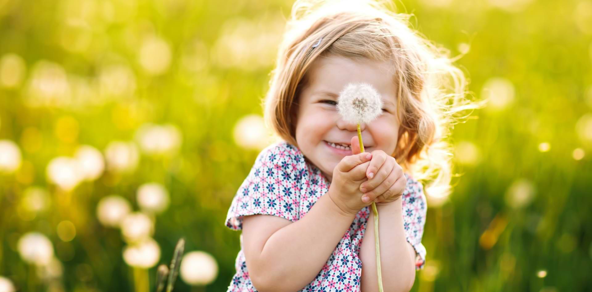 Ein Mädchen hält eine Pusteblume in der Hand